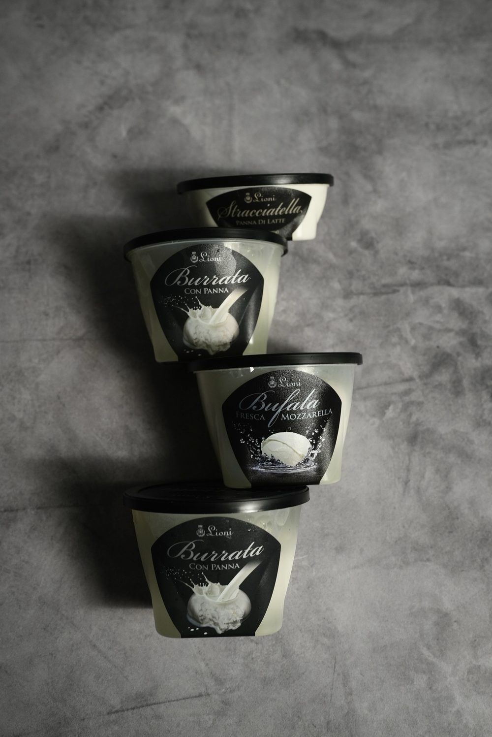 Four Lioni cups stacked: stracciatella panna di latte, burrata con panna, and bufala fresh mozzarella.