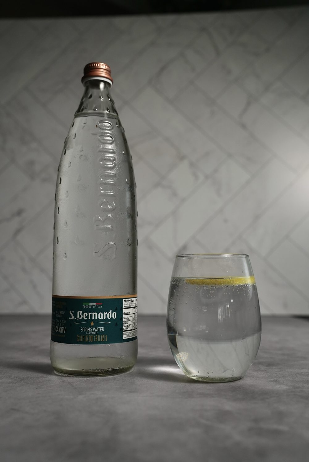 A one-litre glass bottle of S. Bernardo sparkling spring water beside a filled glass.